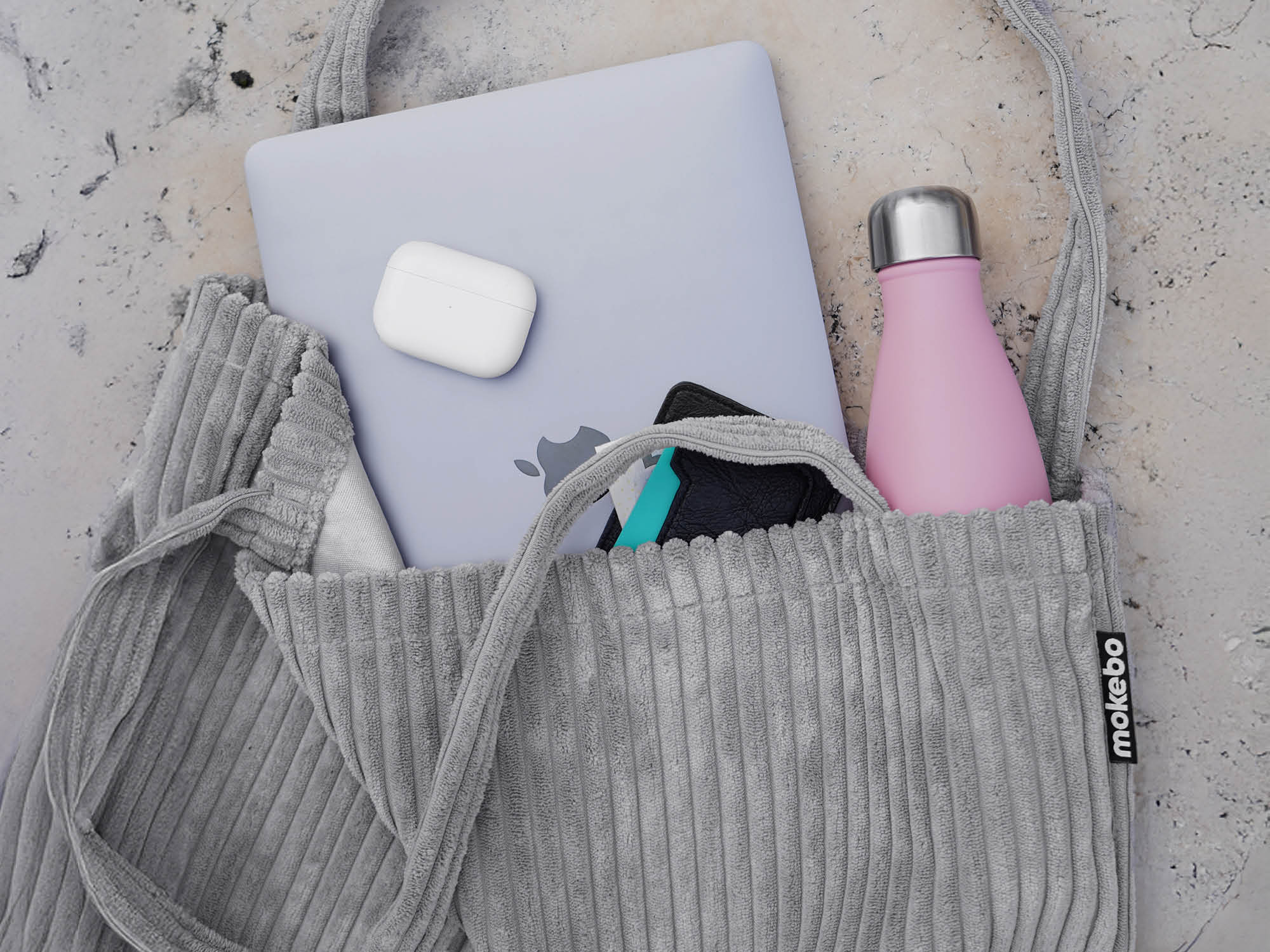 Sac fourre-tout gris clair en toile de jute avec ordinateur portable et casque, vue de dessus sur sol en pierre