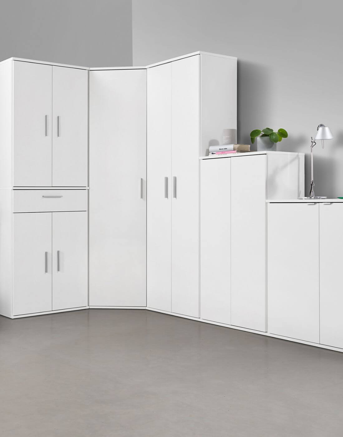 Meuble de rangement modulaire, plusieurs armoires multifonction blanches alignées dans un coin de pièce. Tous les meubles sont