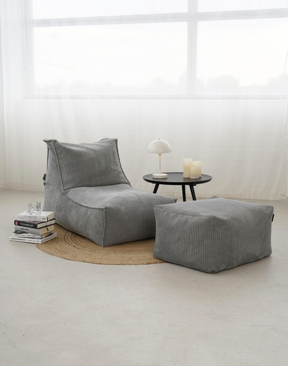Pouf bean bag en velours côtelé 'Der Gelassene' sur tapis rond marron avec table basse et pile de livres à côté