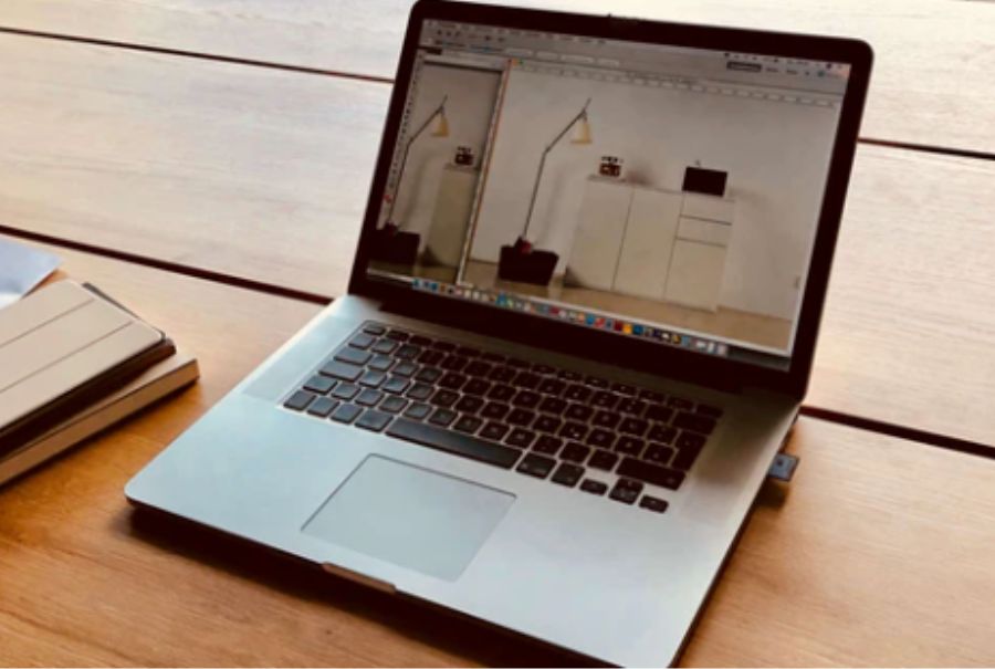 Ordinateur portable ouvert sur une table en bois avec une lampe et une commode visibles à l'écran