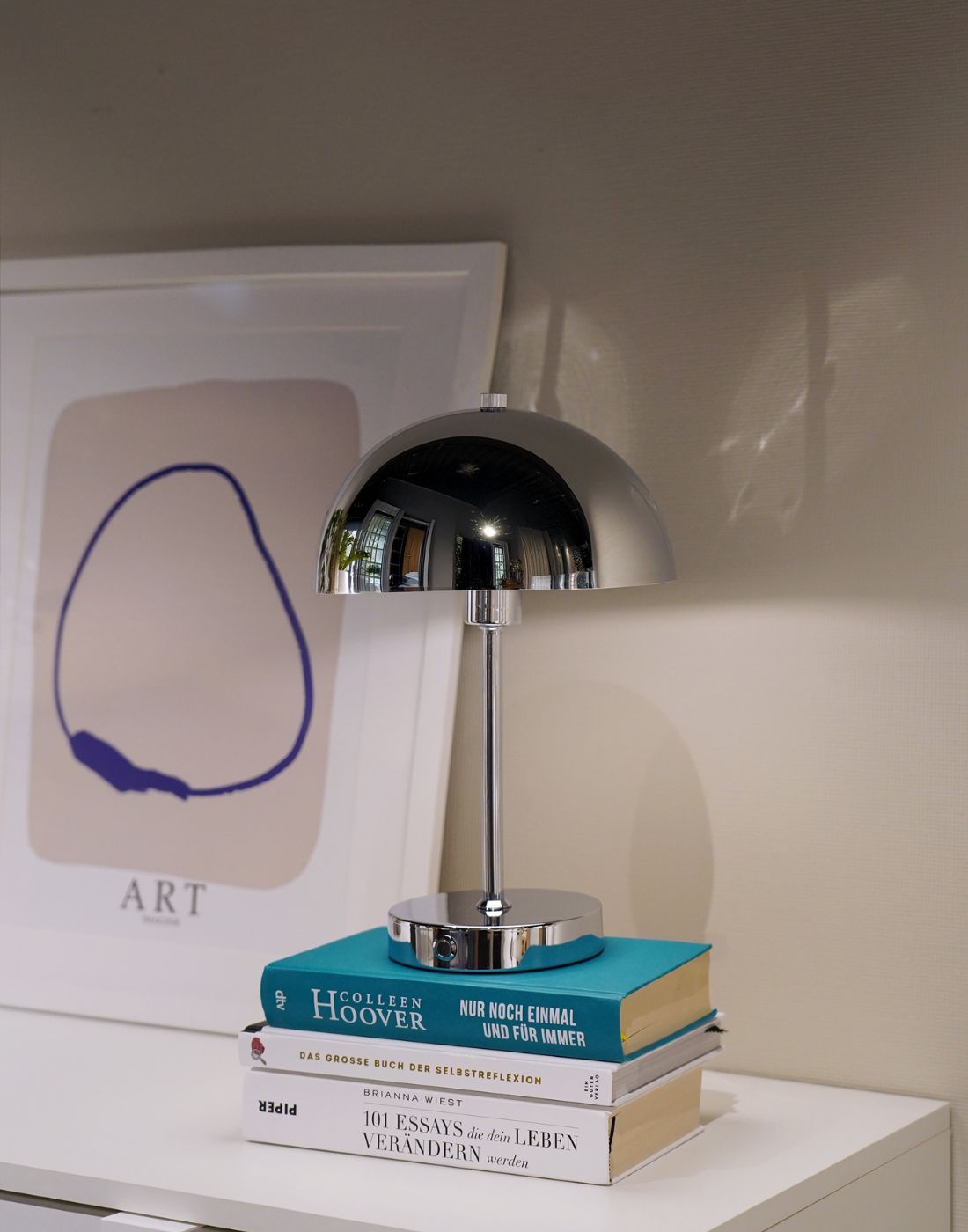 Lampe de table LED sans fil chromée posée sur une pile de livres